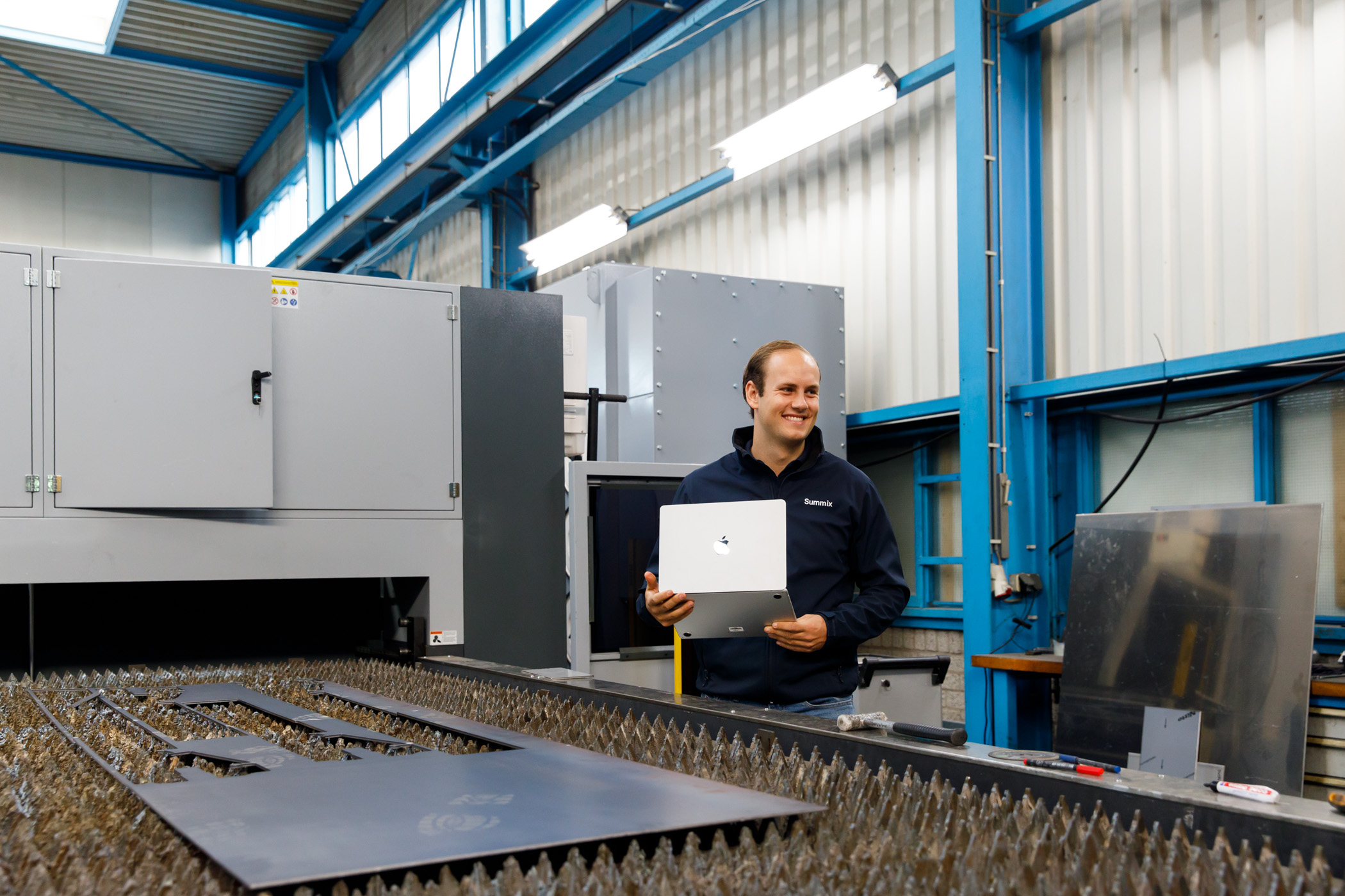 Summix-collega met laptop bij een lasersnijmachine