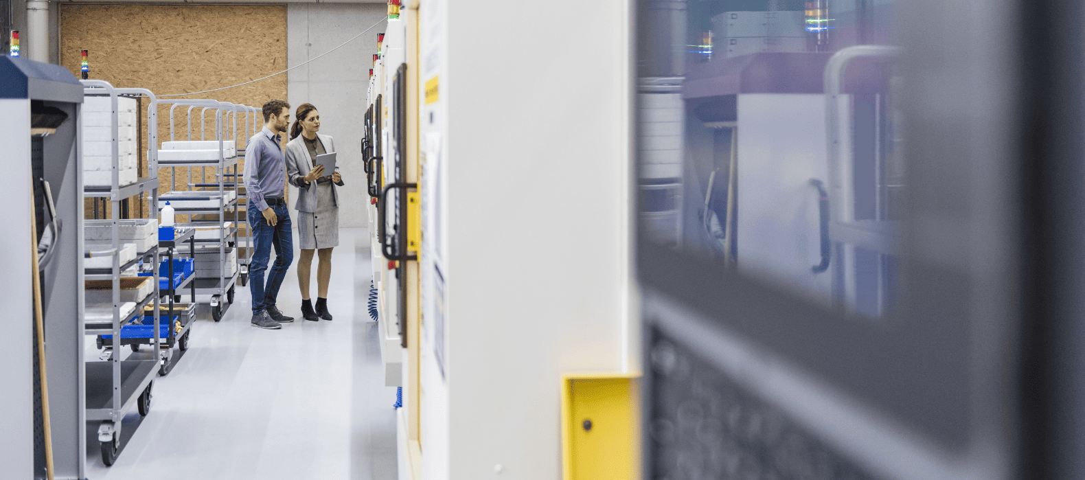 Twee medewerkers overleggen bij een machine in de productiehal van Ploeg Kozijnen