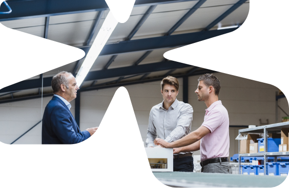 Drie mannen in gesprek op de fabrieksvloer, bijgesneden in de vorm van het Summix-beeldmerk